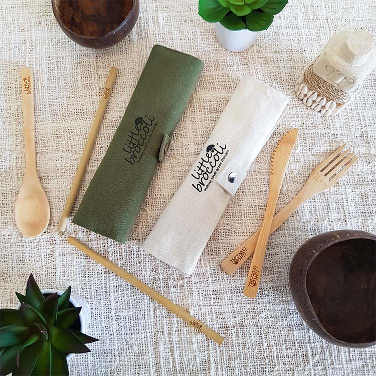 Top shot of Bamboo Cutlery set including travel puch in green and natural colours, knife, fork, spoon and straw engraved with little broccoli logo on table