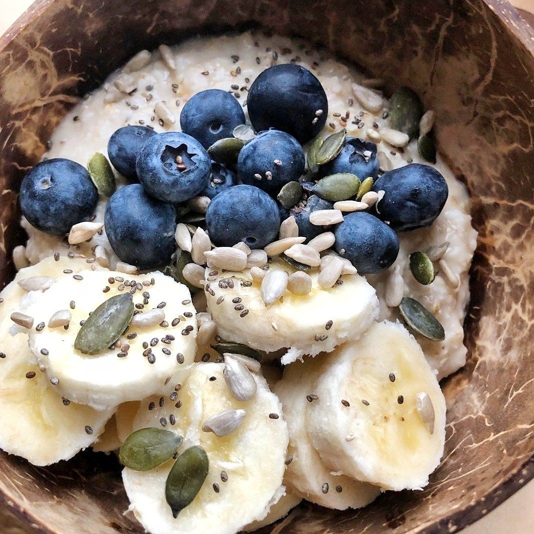 Oats topped with blueberries, banana and sunflower seeds. Served in a coconut bowl.