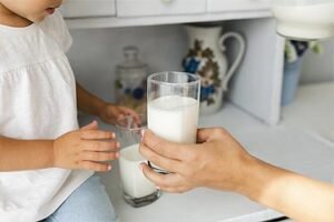 A mom hands her child a glass of vegan plant based milk